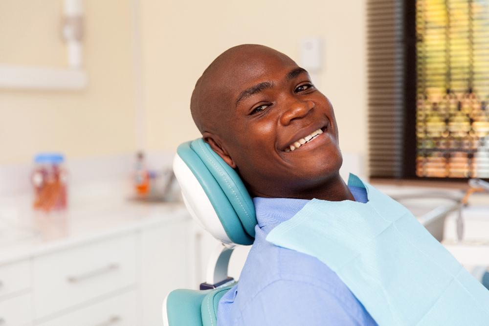 man sitting in dental exam chair smiling l dentist near me