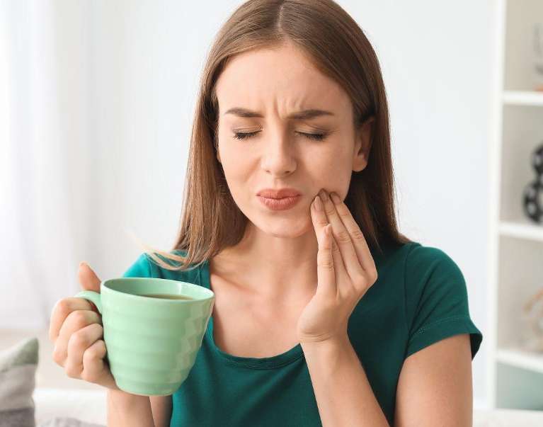 woman holding her left cheek