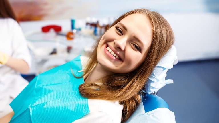 woman smiling in dentist exam chair | dental implants white bear lake mn