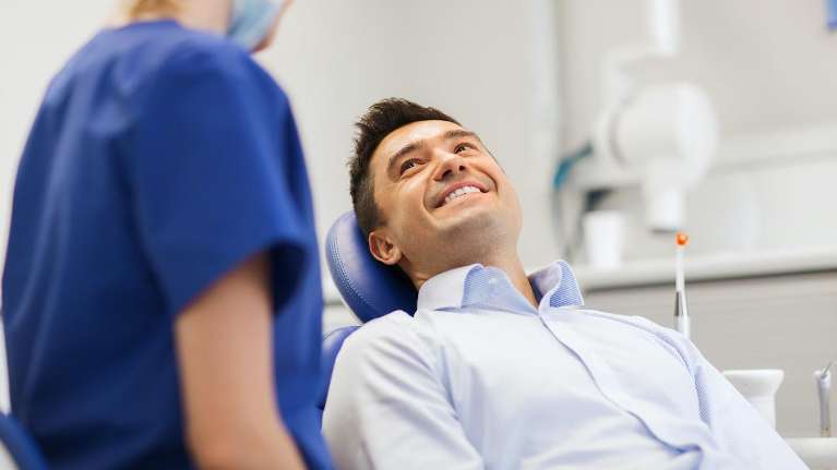 man smiling in dentist exam chair | dental crowns white bear lake mn
