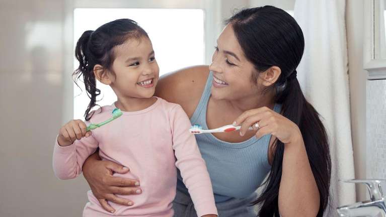 mom and daughter holding toothbrush