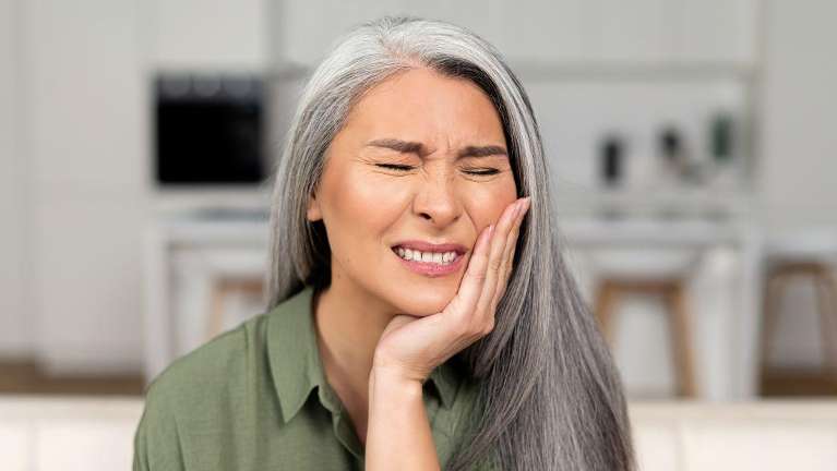 woman in pain holding her left cheek