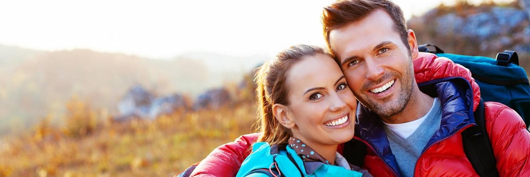 young couple hiking and smiling l cosmetic dentist white bear lake